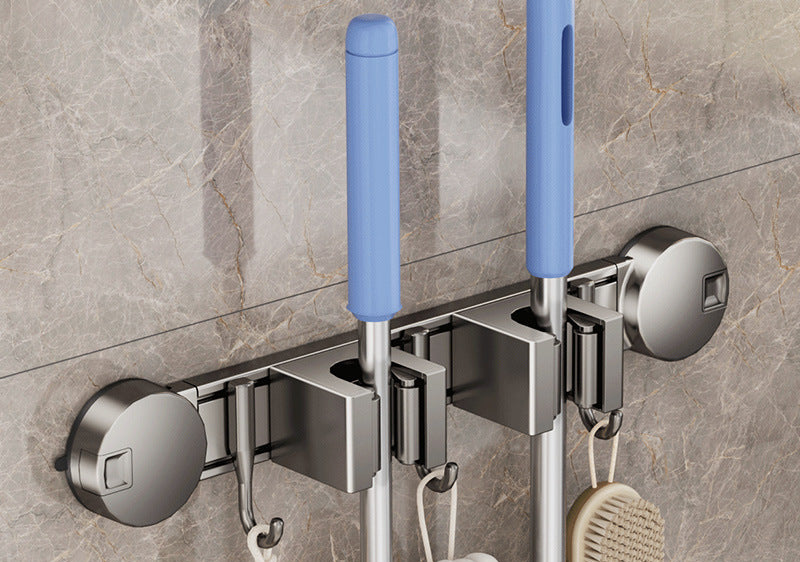 Wall-mounted cleaning tool holder with blue handles on a tiled wall.